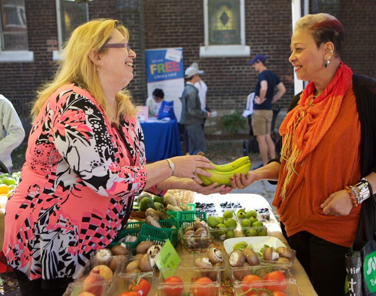 A woman talking to a vendor of at a market