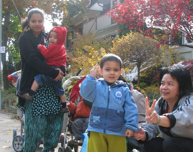 A child giving a peace sign, with family standing outside