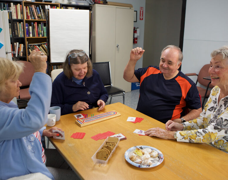 Seniors gathered around the table playing games and having snacks