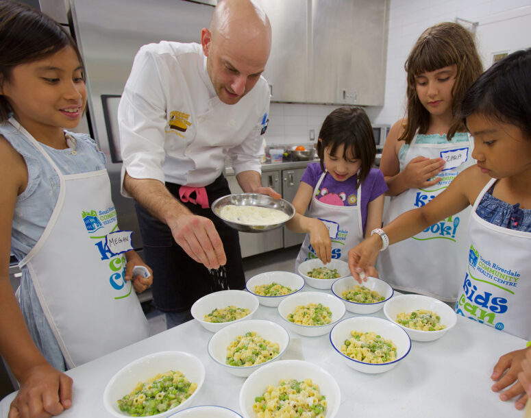A chef teaching youth how to cook in a kitchen