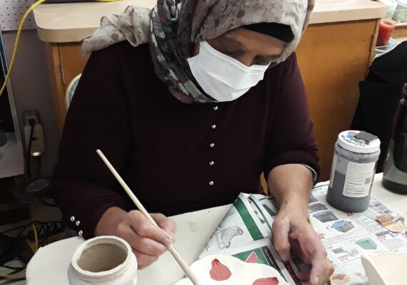 Woman painting her clay piece to get ready for firing