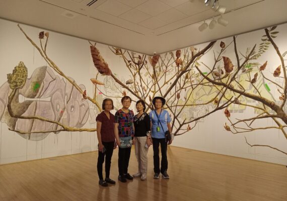 A group of women stand in front of an art wall