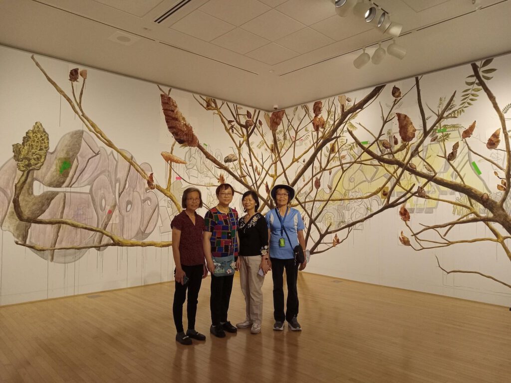 A group of women stand in front of an art wall