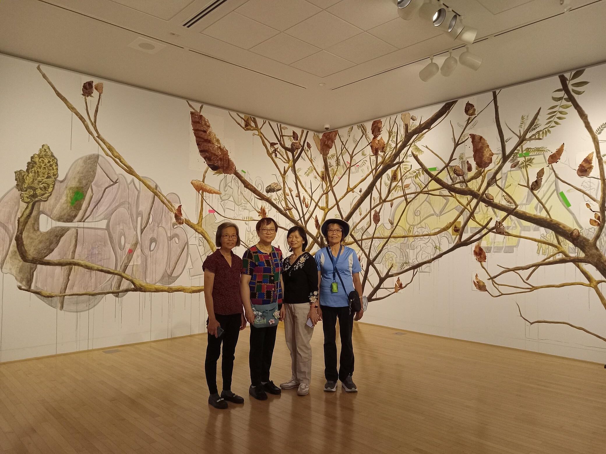 A group of women stand in front of an art wall