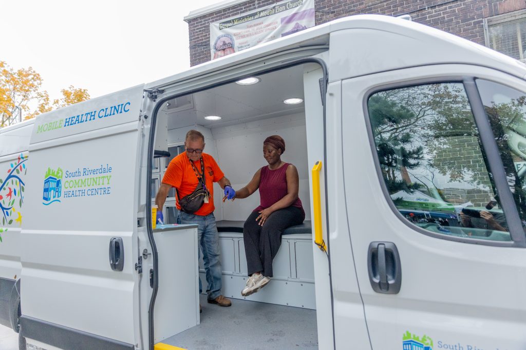 Mobile clinic van door is open to show a person receiving treatment from a health professional