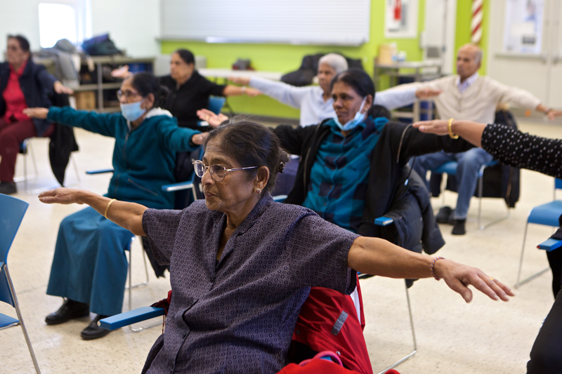 A group of seniors are seated with arms outstretched for exercise
