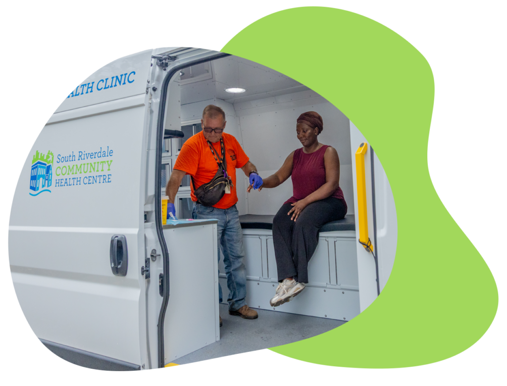 Mobile clinic van door is open to show a person receiving treatment from a health professional