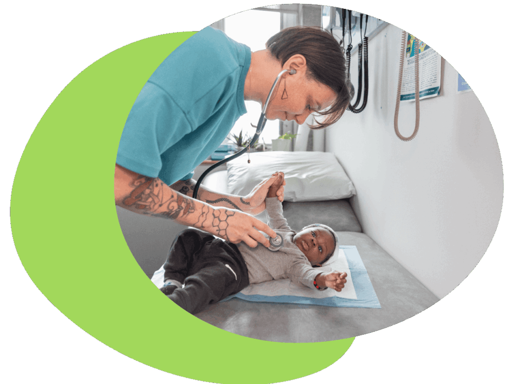 A midwife places a stethescope on an infant who is lying on an examination table