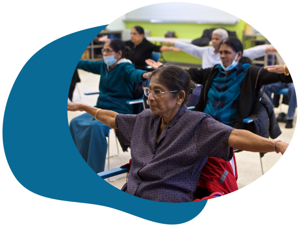 A group of seniors are seated with arms outstretched for exercise