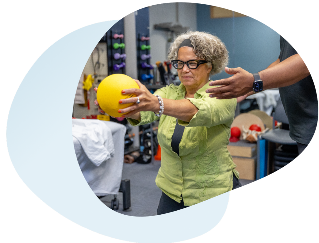 A woman stands with her arms outstretched and holding a ball