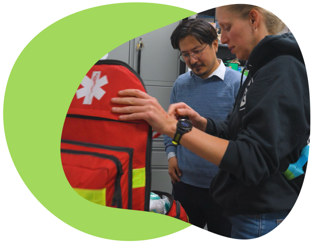 Two people stand and look at an open medical supply bag